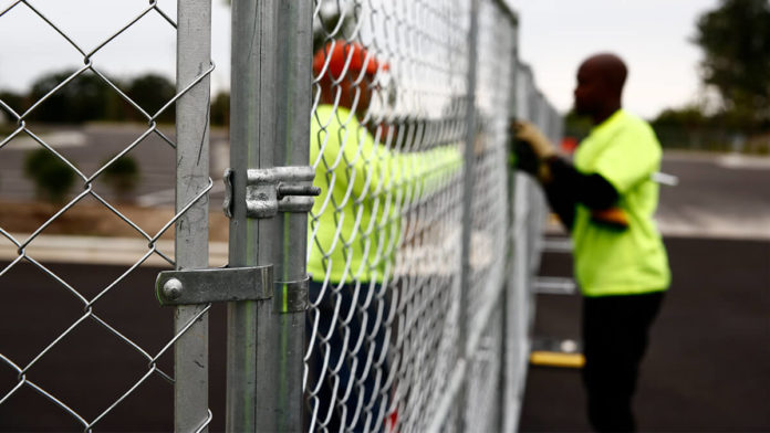 two people putting up a chain-link fence